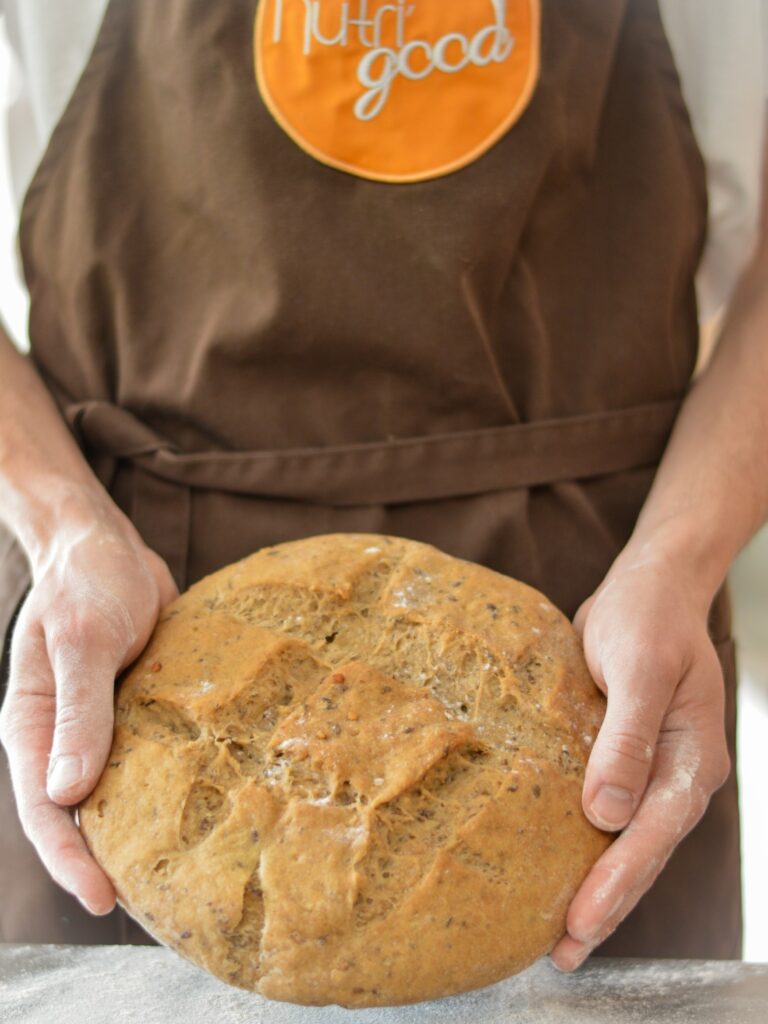 un boulanger tient dans ses mains une tourte de pain sans gluten